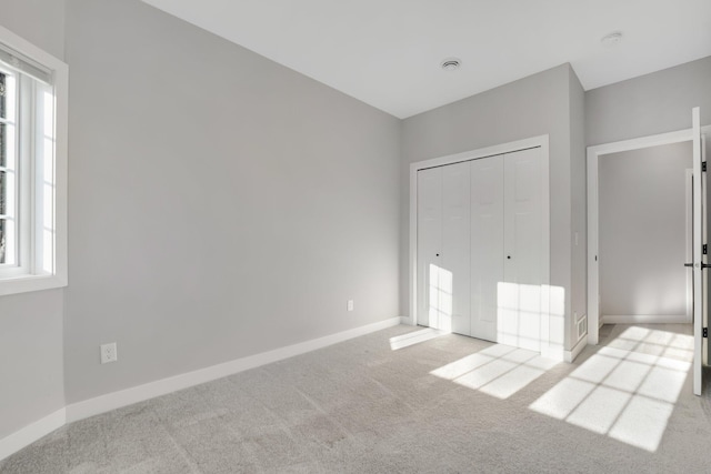 unfurnished bedroom featuring light carpet and a closet