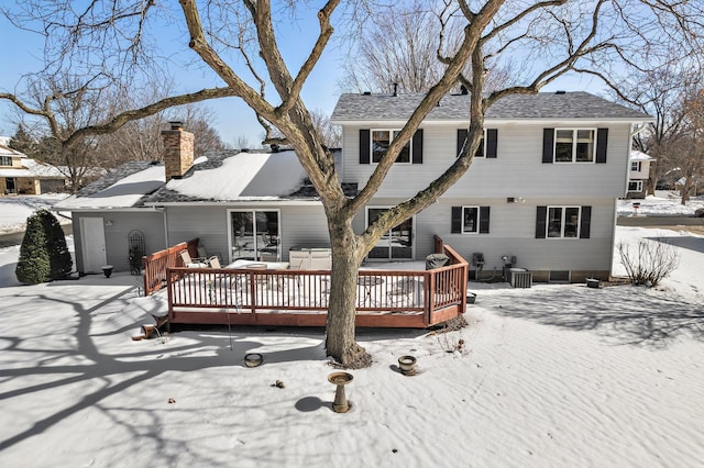 snow covered house featuring a wooden deck and a chimney