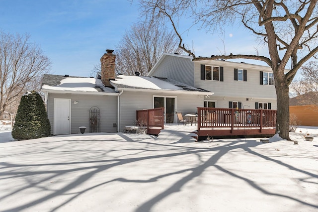 snow covered property featuring a chimney and a wooden deck