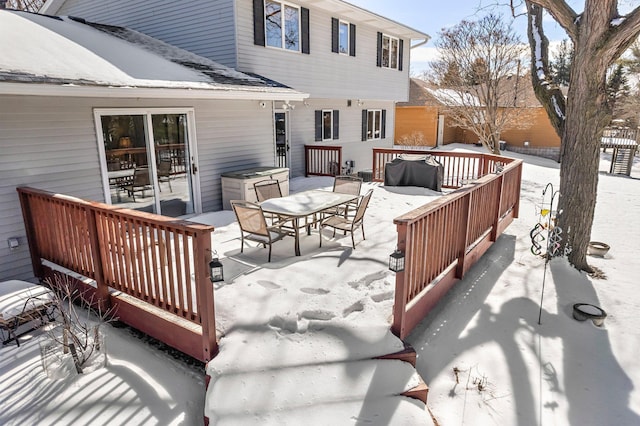 snow covered deck featuring outdoor dining area and a grill