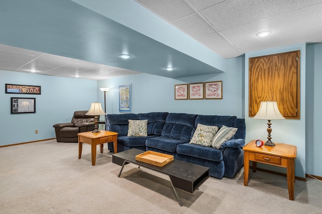 carpeted living area featuring a paneled ceiling and baseboards