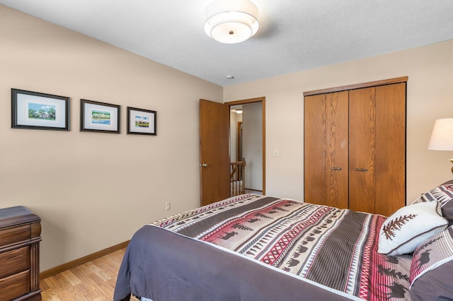 bedroom featuring light wood-style flooring, baseboards, and a closet