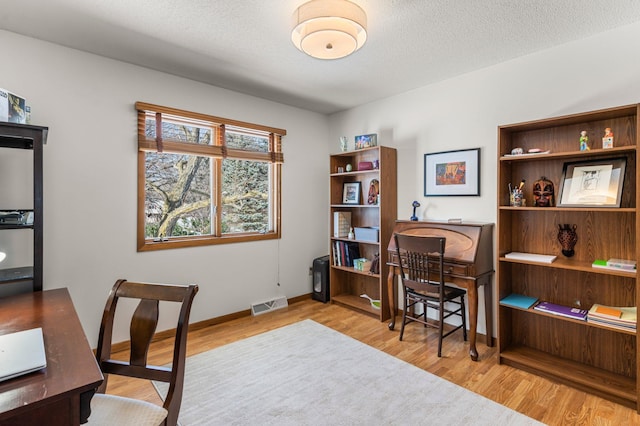 home office featuring visible vents, baseboards, a textured ceiling, and wood finished floors