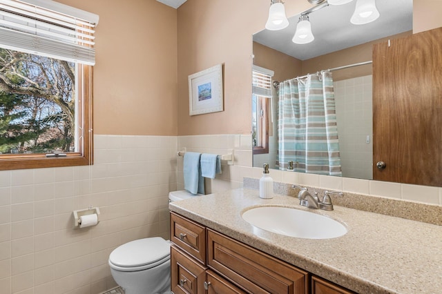 full bathroom with a shower with curtain, toilet, tile walls, wainscoting, and vanity