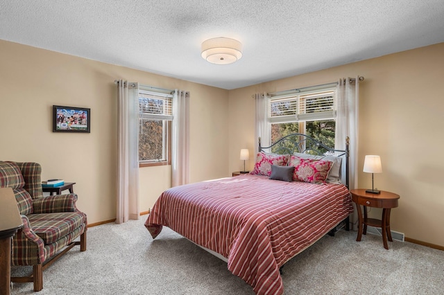 bedroom featuring light carpet, a textured ceiling, and baseboards