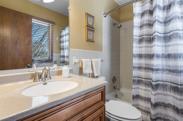 bathroom featuring a wainscoted wall, toilet, vanity, shower / tub combo with curtain, and tile walls