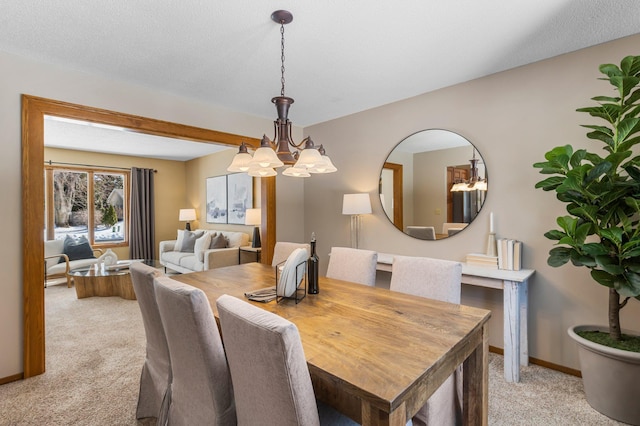 dining space featuring a textured ceiling, an inviting chandelier, baseboards, and light carpet