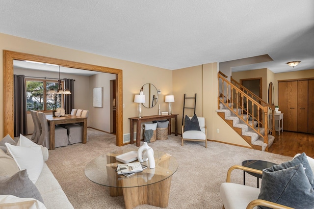 living area with stairs, baseboards, carpet floors, and a textured ceiling