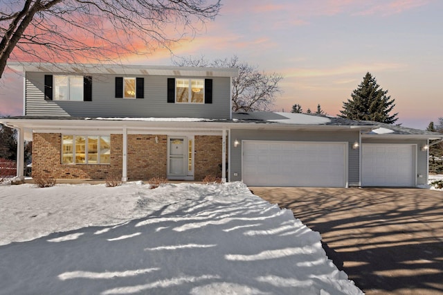 traditional home with brick siding, a garage, and driveway