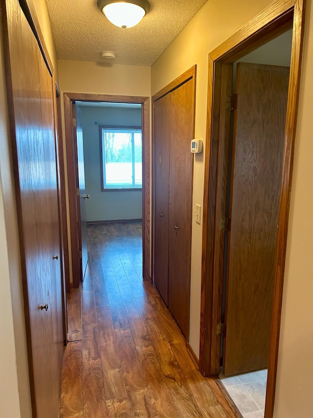 hall with wood-type flooring and a textured ceiling