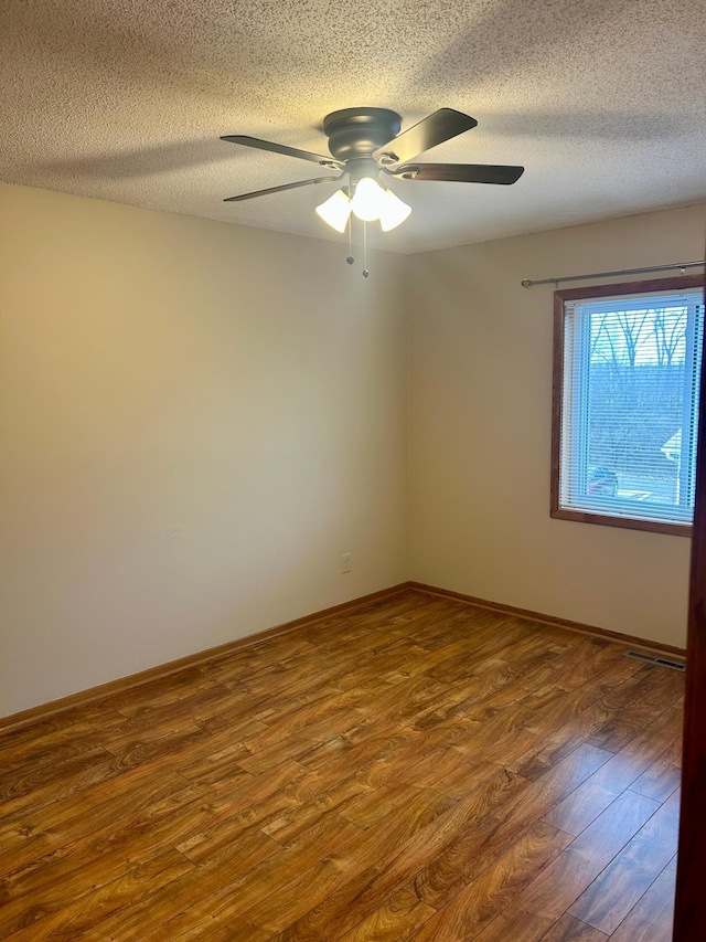 unfurnished room with hardwood / wood-style flooring, ceiling fan, and a textured ceiling