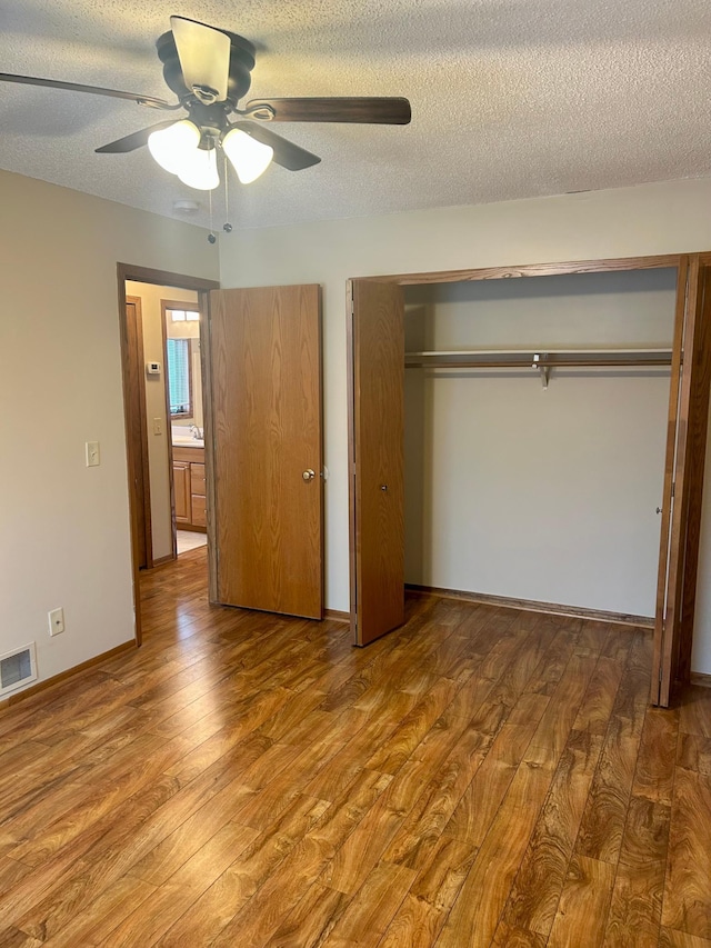 unfurnished bedroom with hardwood / wood-style floors, ceiling fan, a textured ceiling, and a closet