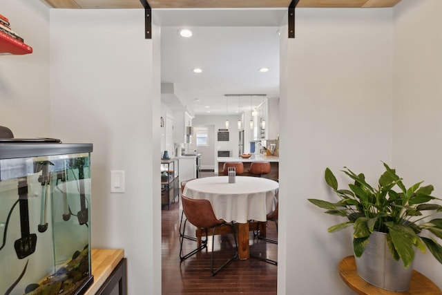 corridor with a barn door and dark hardwood / wood-style floors