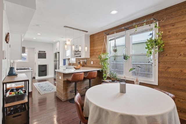 dining room with dark wood-type flooring, sink, and wooden walls