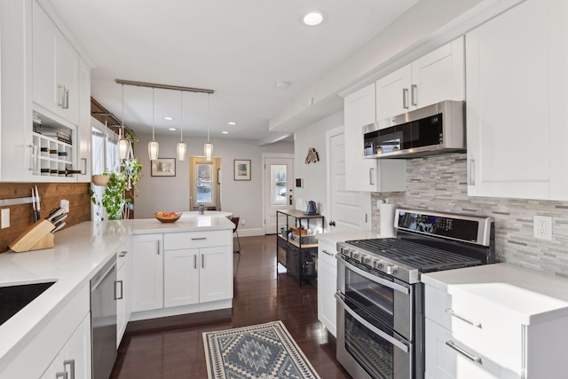 kitchen featuring decorative light fixtures, white cabinets, kitchen peninsula, and appliances with stainless steel finishes