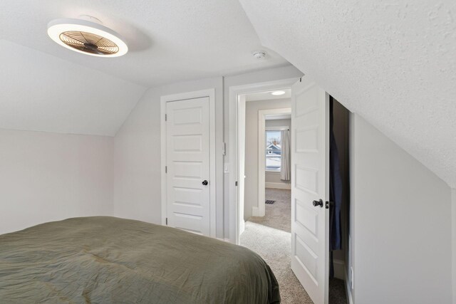 carpeted bedroom featuring a textured ceiling and vaulted ceiling