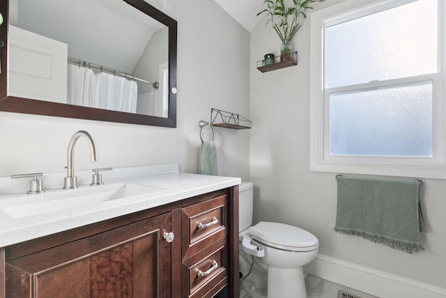 bathroom with toilet, vanity, and lofted ceiling