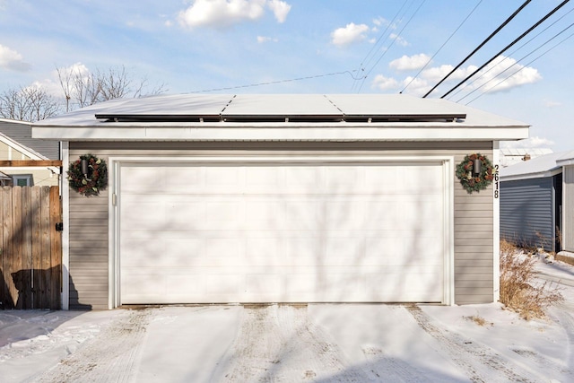 snow covered garage with solar panels