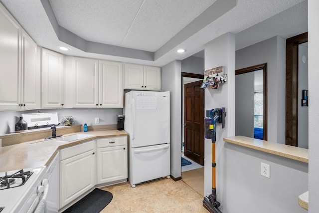 kitchen with range, a textured ceiling, white fridge, and white cabinetry