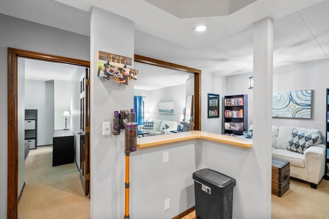 hall featuring light colored carpet and a textured ceiling