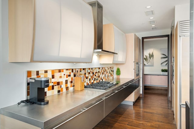 kitchen featuring decorative backsplash, stainless steel gas cooktop, dark wood-type flooring, stainless steel counters, and wall chimney range hood