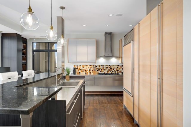 kitchen featuring decorative backsplash, wall chimney exhaust hood, dark wood-type flooring, sink, and pendant lighting