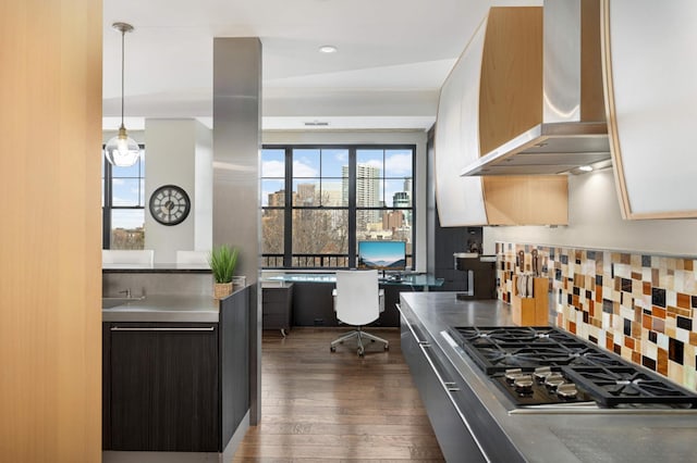 kitchen featuring decorative backsplash, wall chimney exhaust hood, pendant lighting, dark hardwood / wood-style floors, and stainless steel gas stovetop