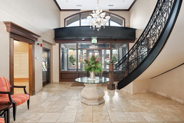 foyer featuring a towering ceiling, crown molding, and a notable chandelier