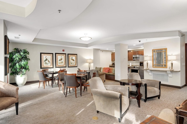 living room with a raised ceiling and light carpet