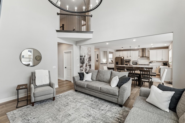 living room featuring an inviting chandelier, a towering ceiling, and light wood-type flooring