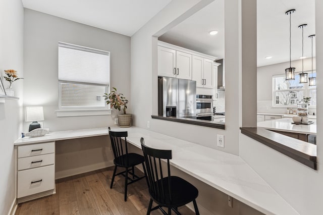 kitchen featuring wood-type flooring, a breakfast bar, built in desk, and stainless steel fridge with ice dispenser