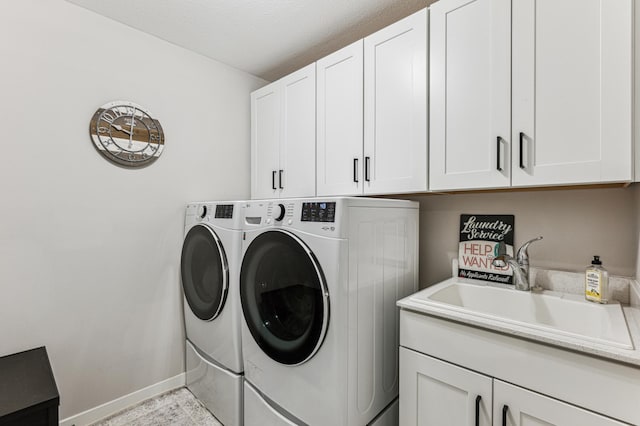 clothes washing area featuring sink, washer and clothes dryer, and cabinets