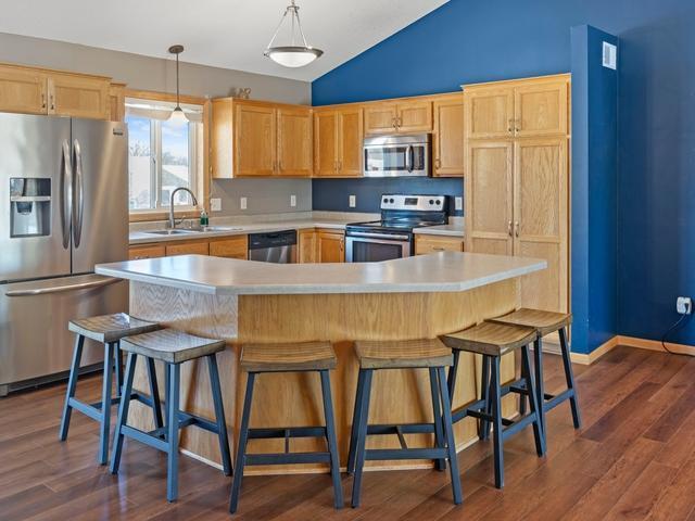 kitchen with sink, hanging light fixtures, appliances with stainless steel finishes, and a kitchen island