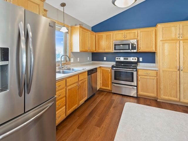 kitchen featuring appliances with stainless steel finishes, lofted ceiling, dark wood-type flooring, sink, and hanging light fixtures