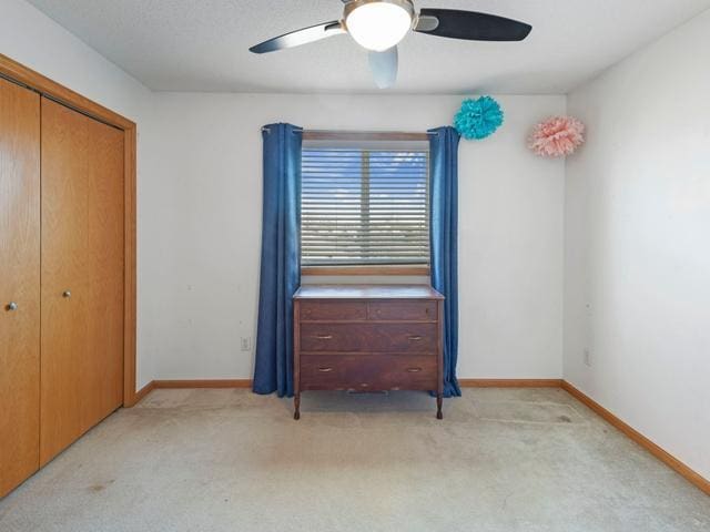 unfurnished bedroom with light carpet, ceiling fan, and a closet