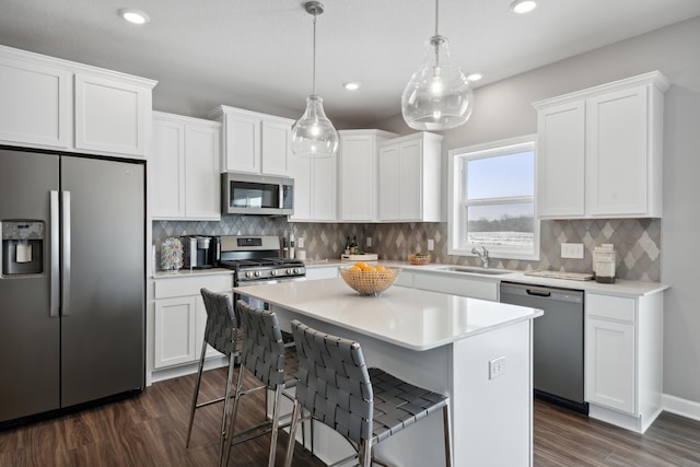 kitchen with white cabinets, appliances with stainless steel finishes, a center island, and pendant lighting