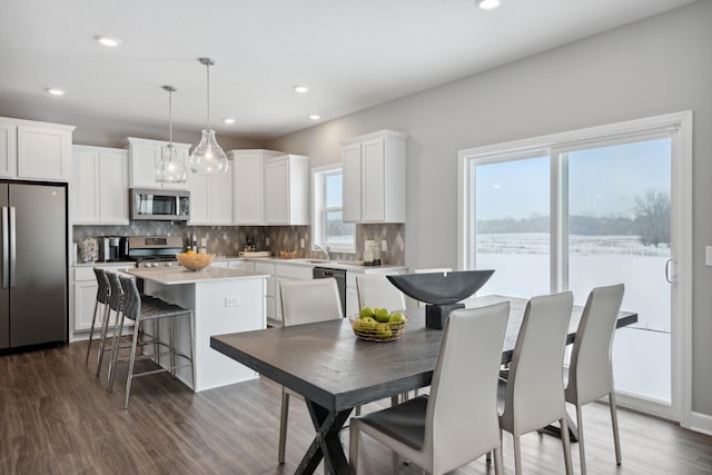 kitchen featuring white cabinetry, dark hardwood / wood-style floors, decorative light fixtures, a kitchen island, and appliances with stainless steel finishes