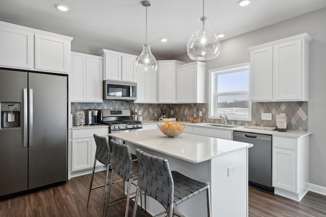 kitchen with white cabinetry, hanging light fixtures, a center island, and appliances with stainless steel finishes