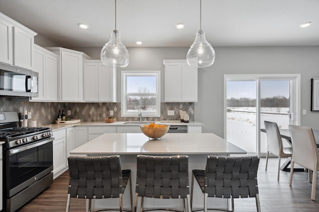 kitchen with white cabinetry, appliances with stainless steel finishes, and hanging light fixtures