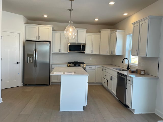 kitchen featuring a kitchen island, appliances with stainless steel finishes, decorative light fixtures, white cabinetry, and sink