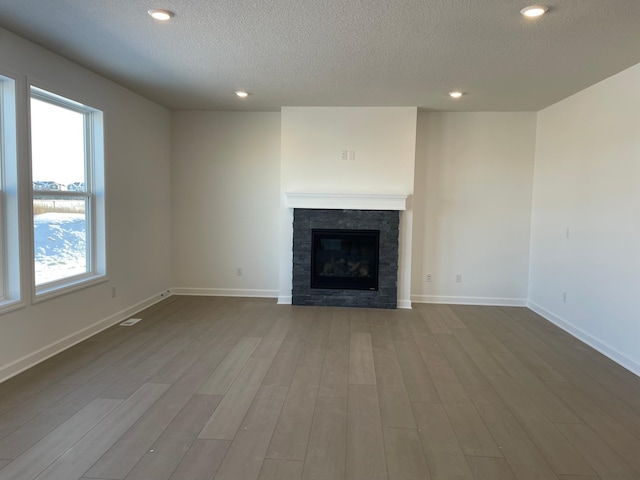 unfurnished living room featuring a fireplace, light hardwood / wood-style floors, and a textured ceiling