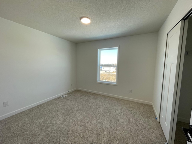 unfurnished bedroom with light colored carpet, a closet, and a textured ceiling