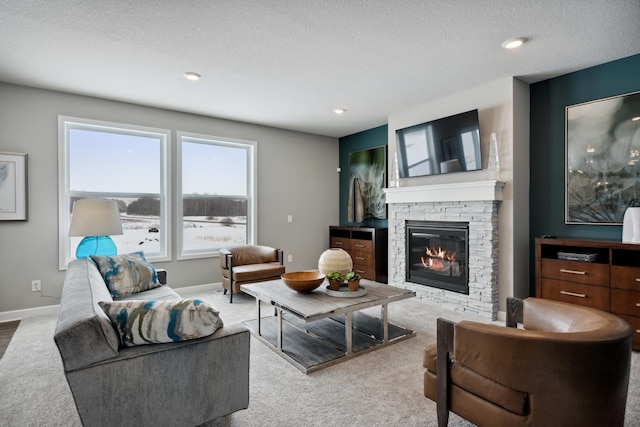 carpeted living room featuring a stone fireplace and a textured ceiling