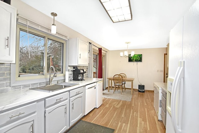 kitchen with backsplash, white cabinets, hanging light fixtures, and sink