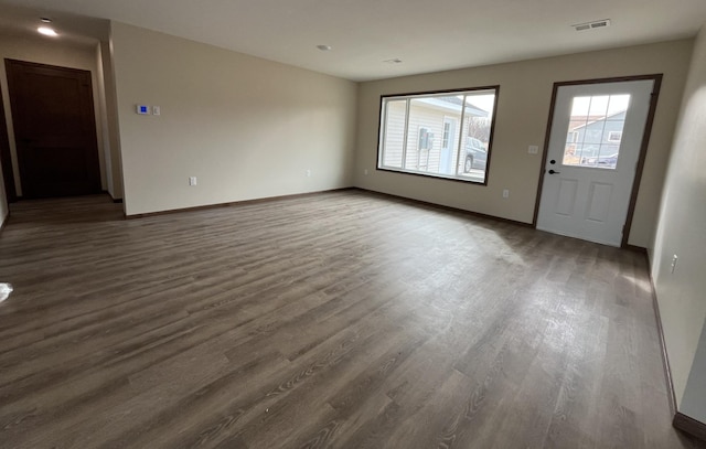 unfurnished living room featuring visible vents, dark wood-type flooring, and baseboards