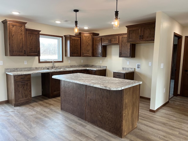 kitchen with baseboards, visible vents, light wood finished floors, a sink, and dark brown cabinets