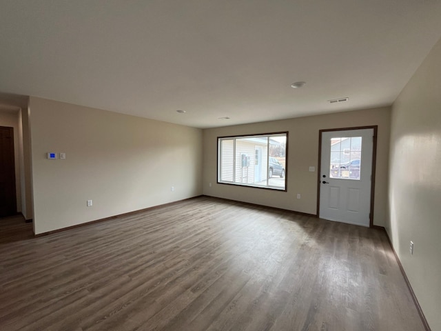 unfurnished living room with visible vents, baseboards, and wood finished floors