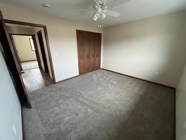 unfurnished bedroom with a closet, a ceiling fan, baseboards, and carpet floors