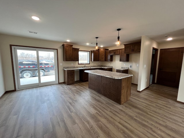146 Front St, Tracy, MN 56175 - kitchen featuring a center island, wood finished floors, dark brown cabinets, recessed lighting, and pendant lighting