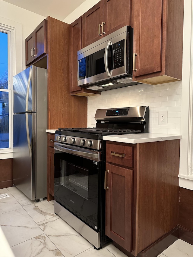 kitchen with dark brown cabinets, backsplash, and stainless steel appliances